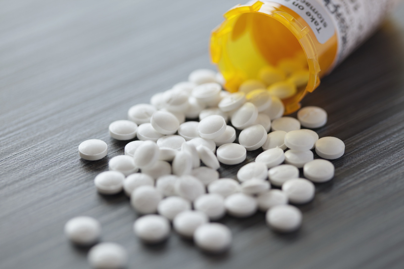 Prescription bottle tipped over with white pills spilling out