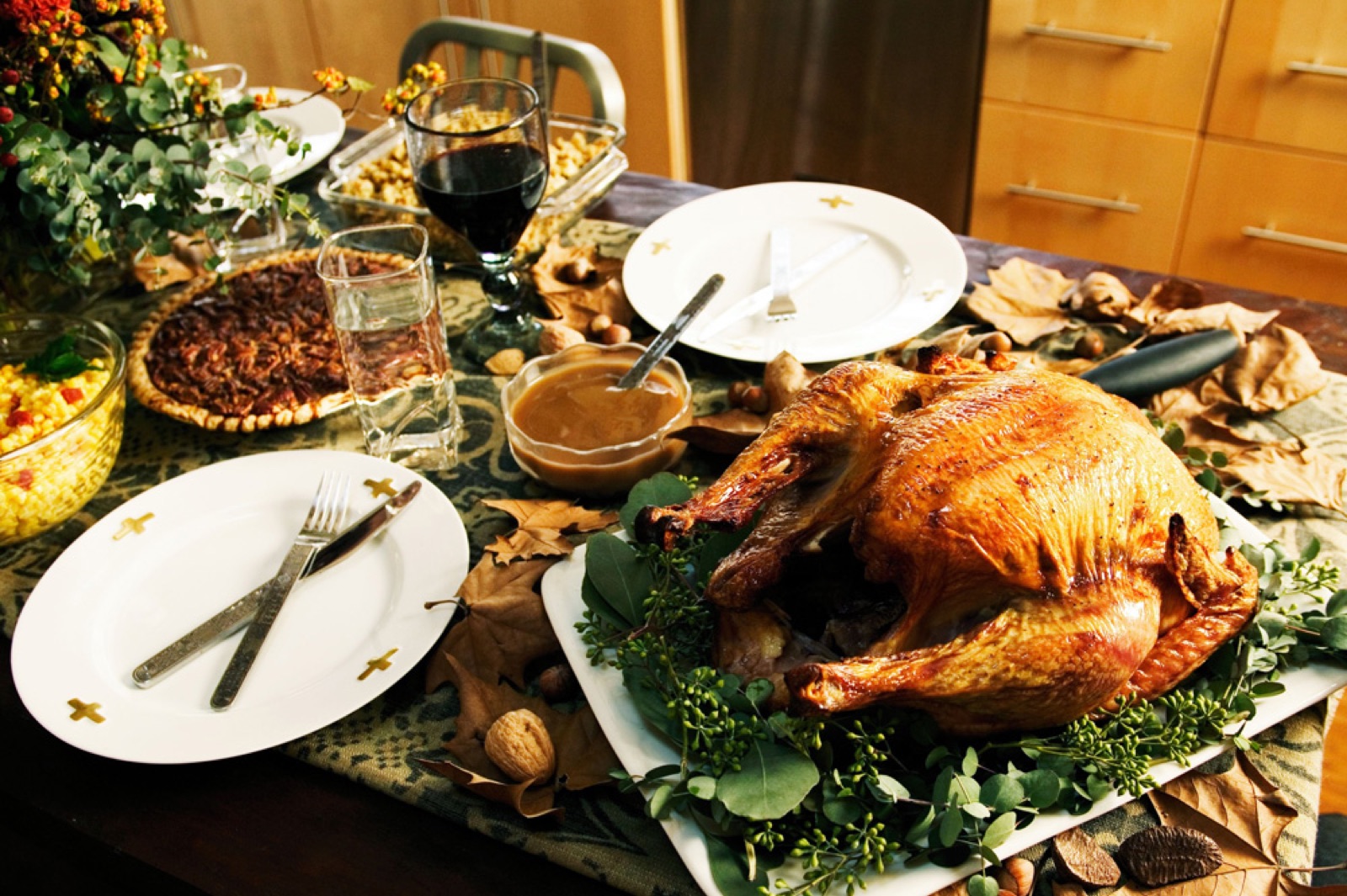 Thanksgiving dinner table with a roasted turkey, pecan pie, and place settings
